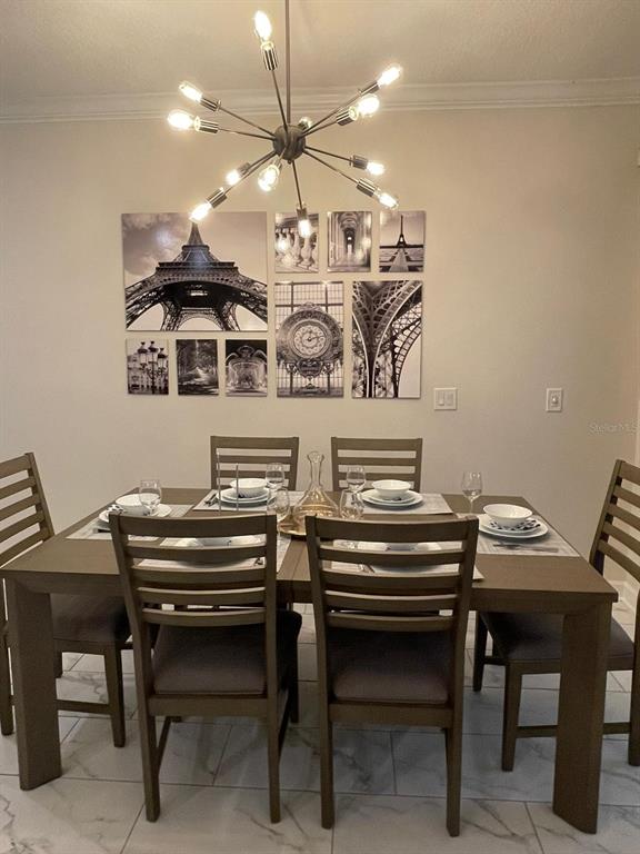 A dining room features a wooden table, six chairs, a sputnik chandelier, and wall art — 1144 CHALLENGE DRIVE, DAVENPORT, FL