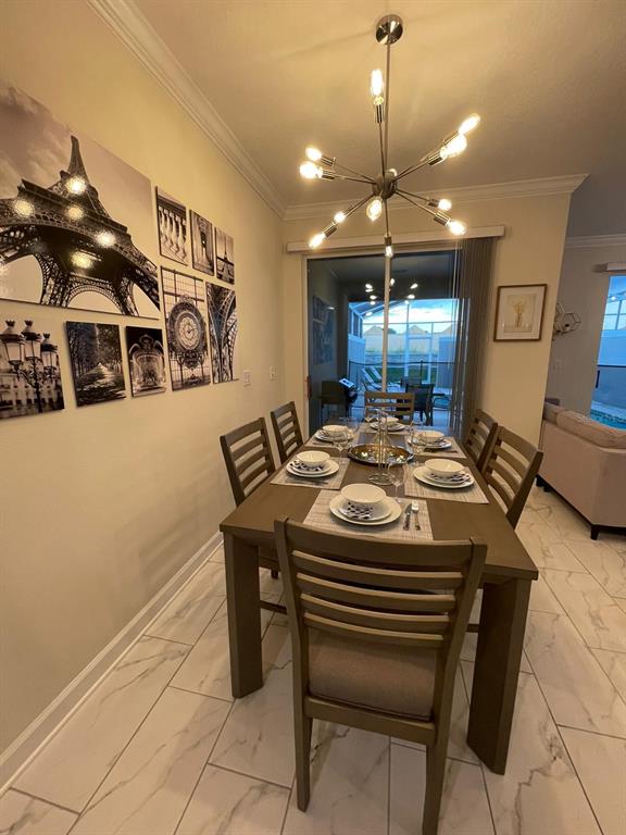 A dining room features a wooden table, chairs, a modern chandelier, and Paris-themed wall art — 1144 CHALLENGE DRIVE, DAVENPORT, FL