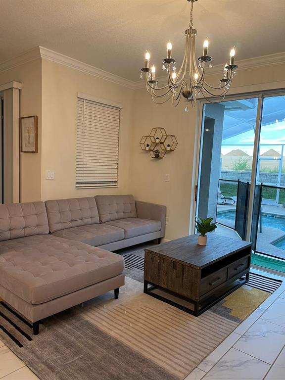 A living room features a gray sectional sofa, a wooden coffee table, and a chandelier — 1144 CHALLENGE DRIVE, DAVENPORT, FL