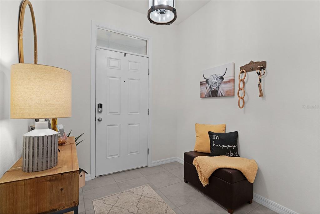 An entryway features a white front door, a storage bench, and a wooden console table — 5365 PINECONE COURT, WILDWOOD, FL