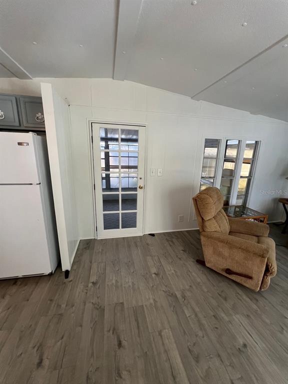A kitchen and living area featuring white walls, wood-look flooring, a refrigerator, and a recliner — 11 SHADY LANE, PALMETTO, FL