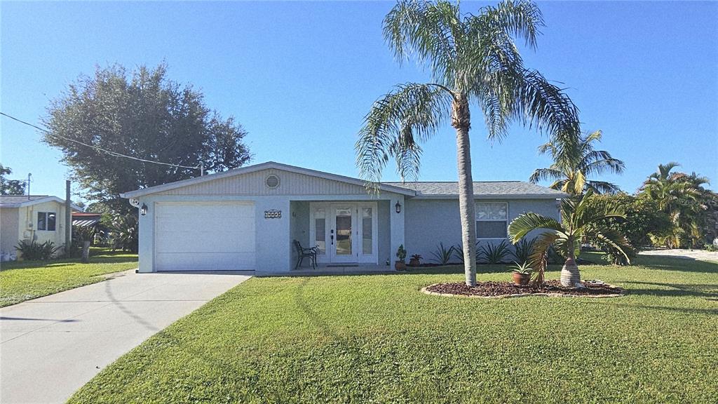 A single-story house with a white garage, front door, and a palm tree in front — 1153 CLARK STREET, ENGLEWOOD, FL