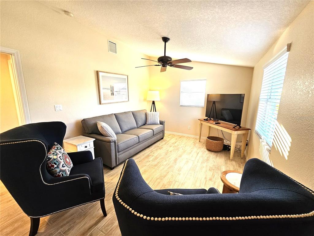 A living room features a grey sofa, two dark armchairs, and a television on a stand — 1153 CLARK STREET, ENGLEWOOD, FL