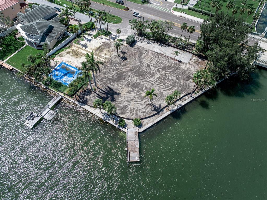 An aerial view shows a vacant waterfront lot with two wooden docks and palm trees — 1 PARADISE LANE, TREASURE ISLAND, FL