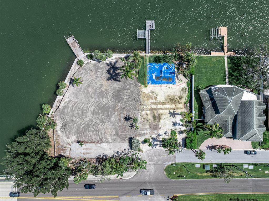 An aerial view shows a waterfront lot with a pool, a dock, and an adjacent house — 1 PARADISE LANE, TREASURE ISLAND, FL