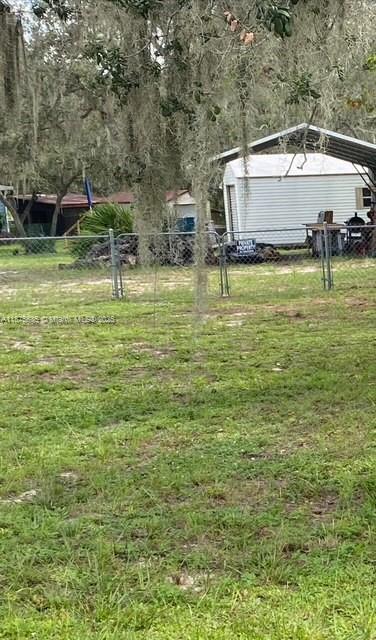 A white shed with a metal carport sits behind a chain-link fence in a yard — 6005 Lake Front Dr, Sebring FL 33876, SEBRING, FL