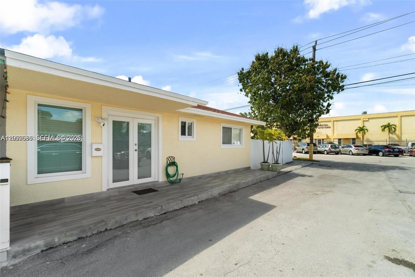 The exterior of a light yellow building features a gray tiled porch and double glass doors — 330 W 74th Pl # 330, Hialeah FL 33014, HIALEAH, FL