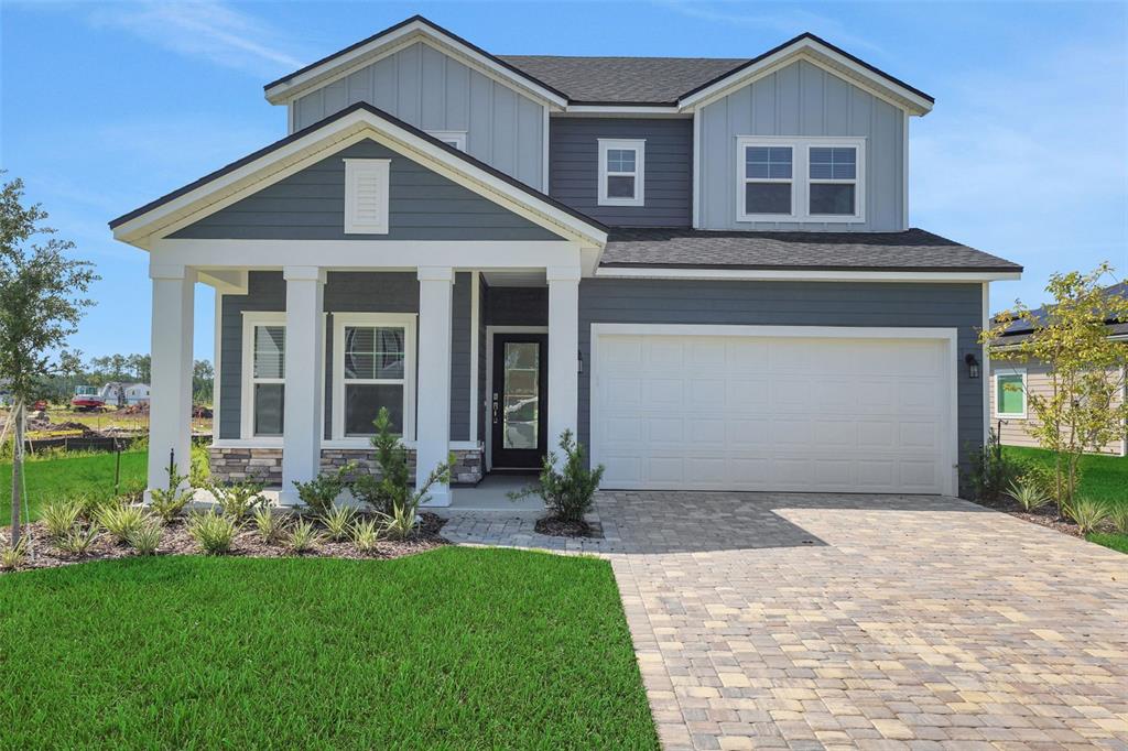 A two-story house with gray siding, a white-pillared porch, and a paved driveway — 864 BROOK FOREST DRIVE, ST AUGUSTINE, FL