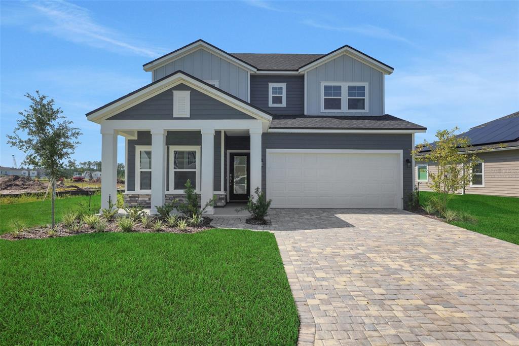 A two-story house with dark gray siding, a white-pillared porch, and a paved driveway — 864 BROOK FOREST DRIVE, ST AUGUSTINE, FL