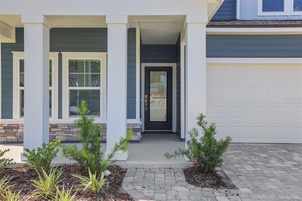 The exterior of a house features a covered porch, a front door, and a garage — 864 BROOK FOREST DRIVE, ST AUGUSTINE, FL