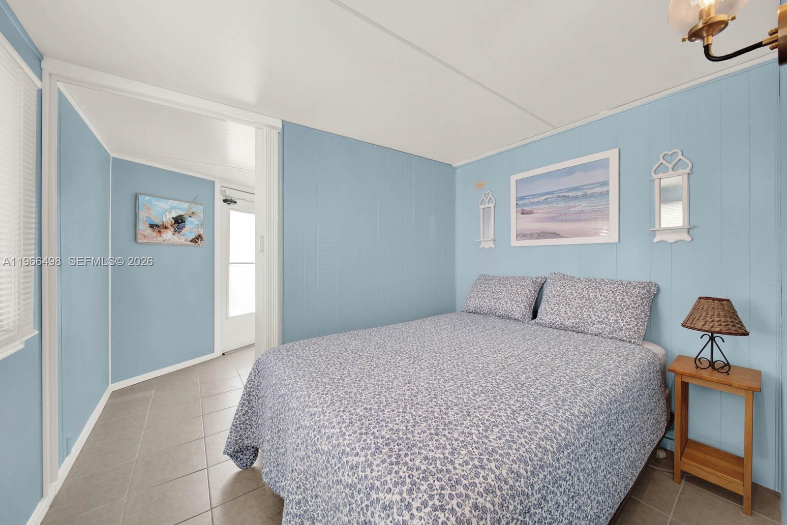 A bedroom features light blue paneled walls, a patterned bedspread, and tile flooring — 10725 S Ocean Drive Unit #534, Jensen Beach FL 34957, JENSEN BEACH, FL