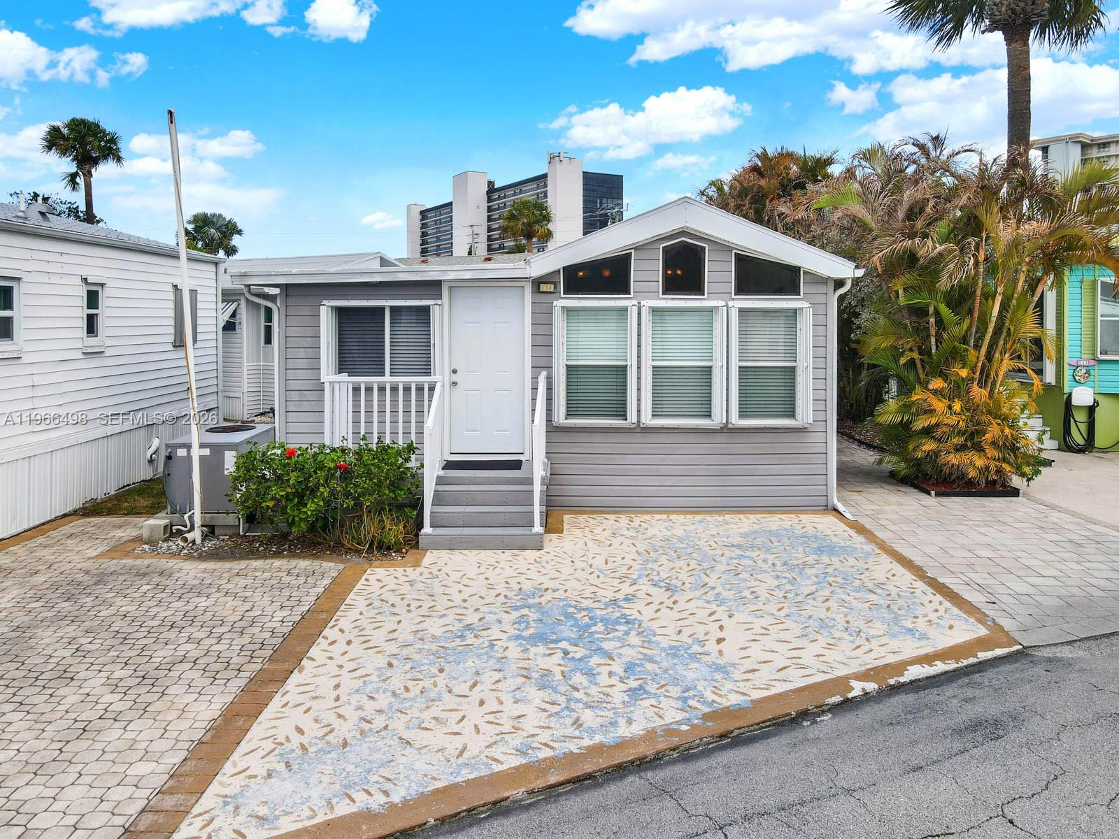 A gray manufactured home with a white door, front steps, and a patterned concrete driveway — 10725 S Ocean Drive Unit #534, Jensen Beach FL 34957, JENSEN BEACH, FL