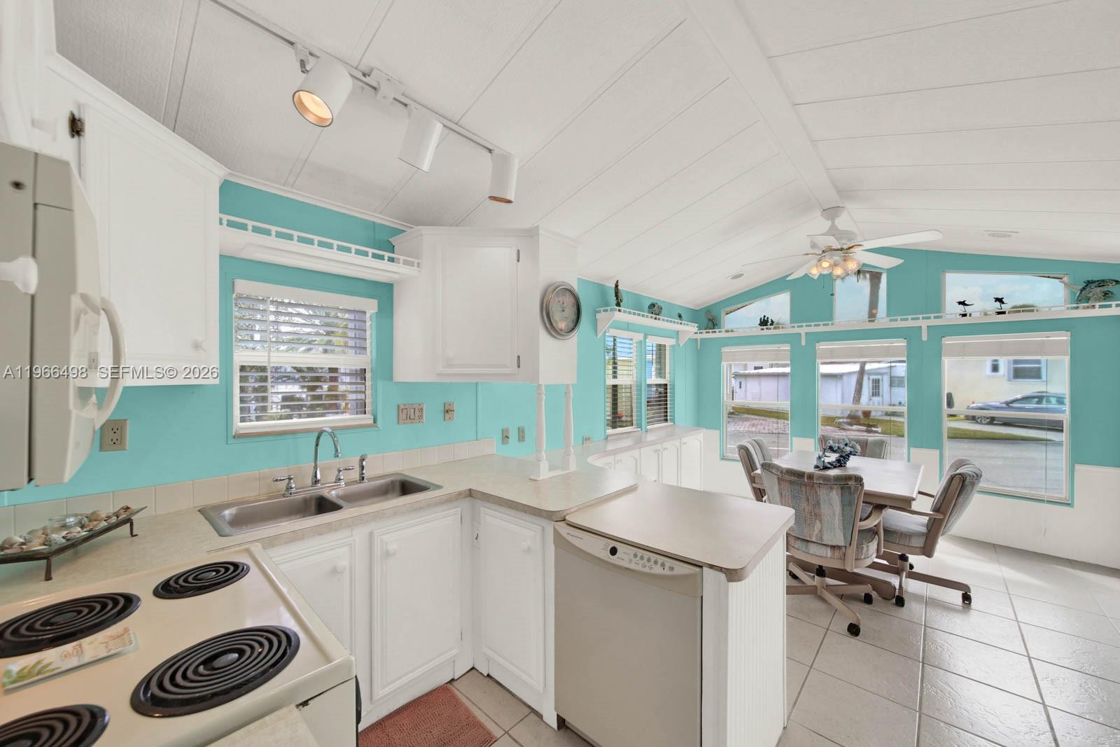 A kitchen with teal walls, white cabinets, and a dining area with large windows — 10725 S Ocean Drive Unit #534, Jensen Beach FL 34957, JENSEN BEACH, FL