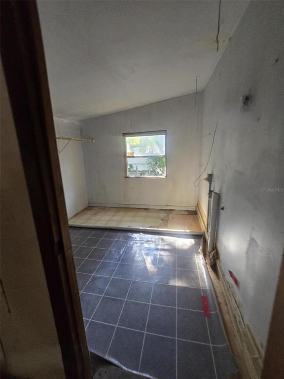 An unfinished room features a sloped ceiling, a single window, and partially installed floor tiles — 1331 DENA STREET, JACKSONVILLE, FL