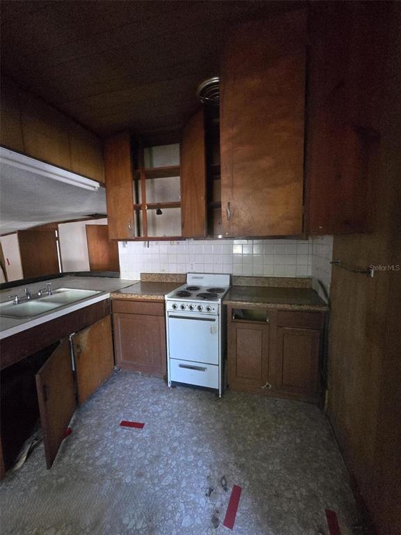 A dated kitchen features wood cabinets, a white stove, and a double-basin sink — 1331 DENA STREET, JACKSONVILLE, FL