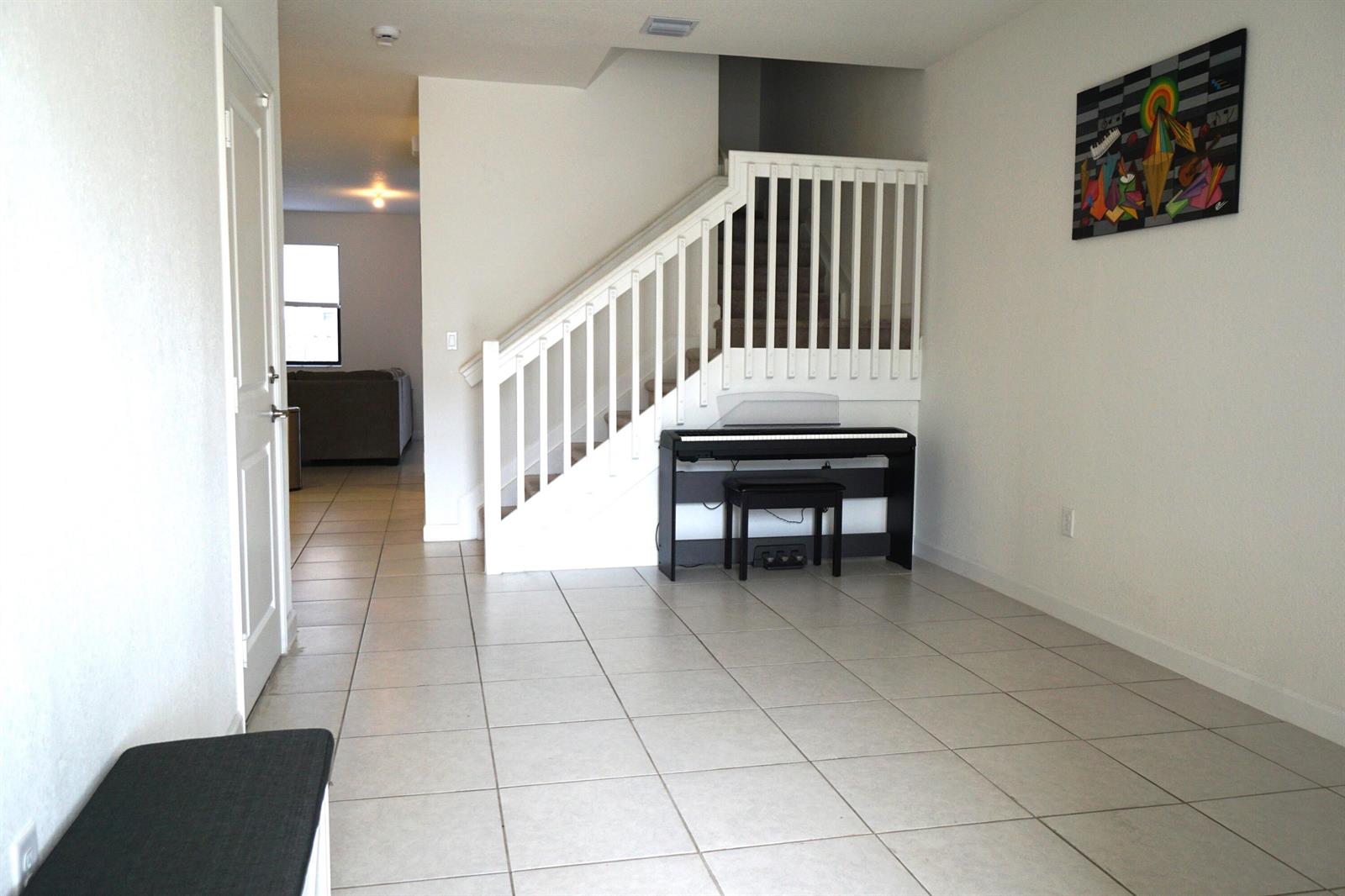 A tiled entryway features a staircase with white railings, a digital piano, and wall art — 23010 SW 128th Place, Miami FL 33170, MIAMI, FL