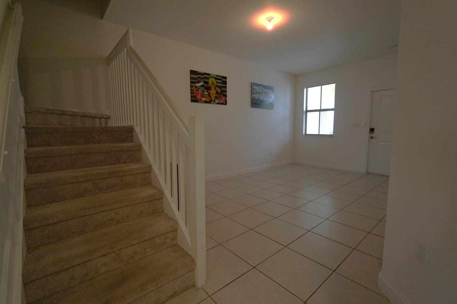 A carpeted staircase with a white railing leads up from a tiled living area — 23010 SW 128th Place, Miami FL 33170, MIAMI, FL