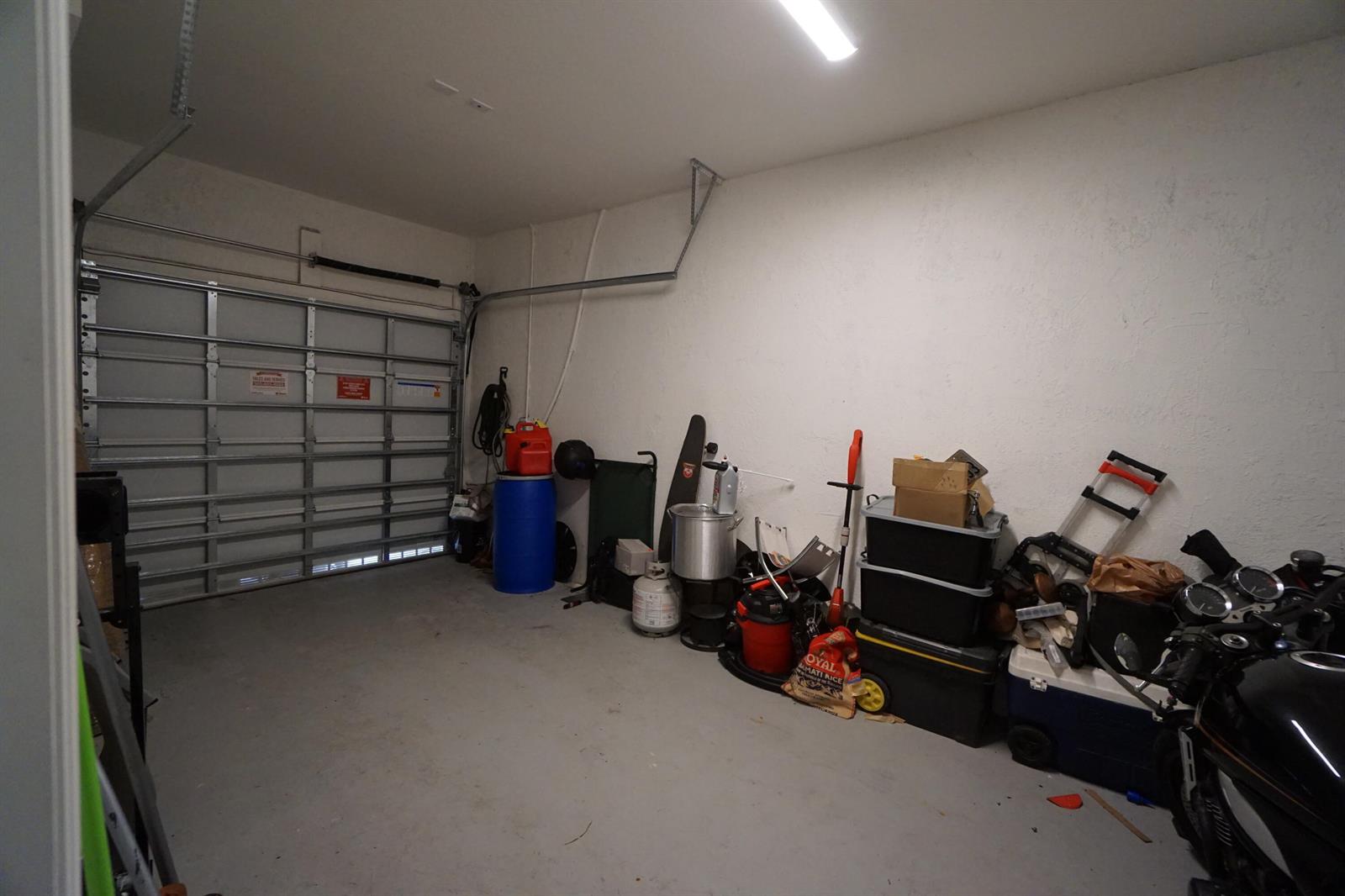 A cluttered residential garage with a concrete floor, white walls, and a metal door — 23010 SW 128th Place, Miami FL 33170, MIAMI, FL