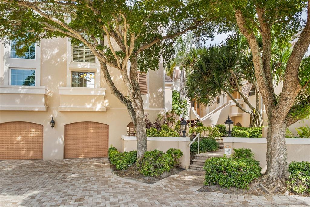 A beige multi-story building with two garages and a landscaped entrance with stone steps — 1161 COQUILLE STREET UNIT 206, SARASOTA, FL