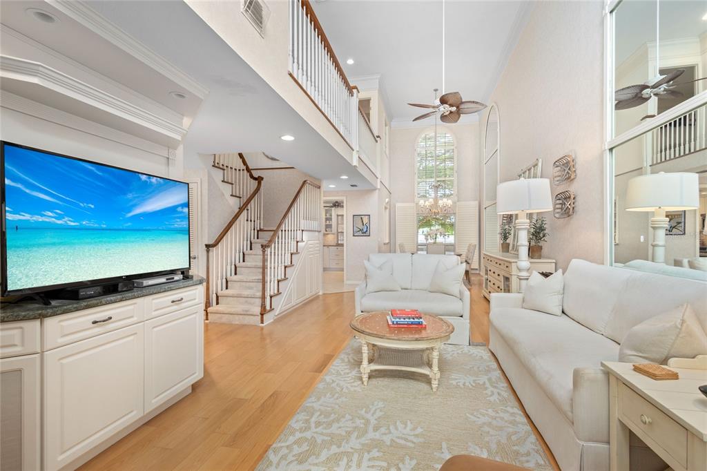 A bright living room features a high ceiling, a staircase, and light-colored furniture — 1161 COQUILLE STREET UNIT 206, SARASOTA, FL