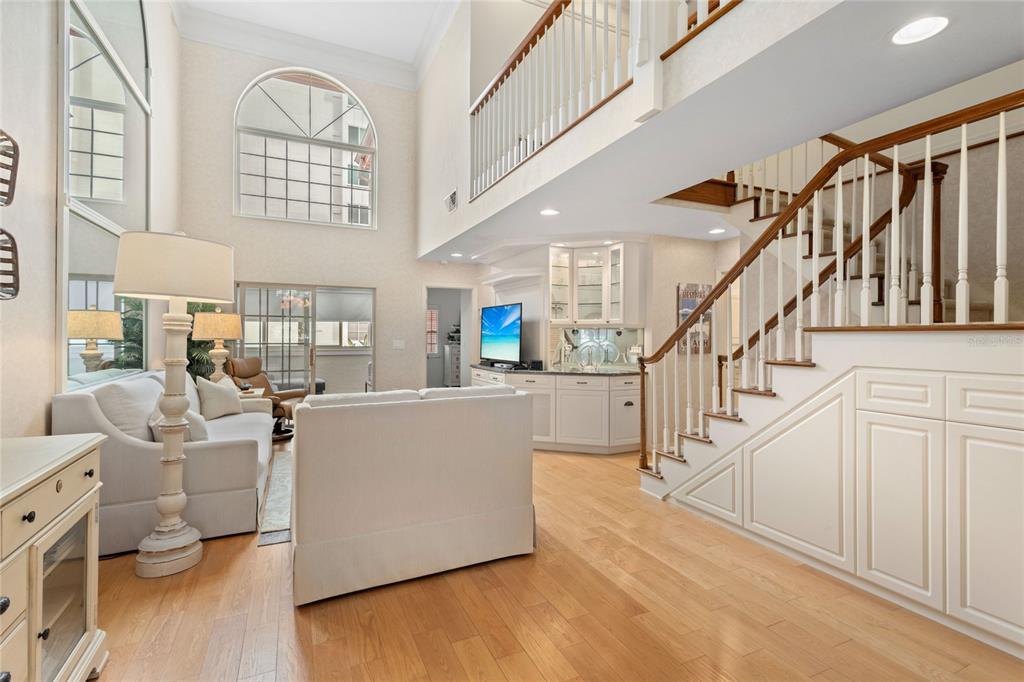 A living room with high ceilings, a staircase, a wet bar, and hardwood floors — 1161 COQUILLE STREET UNIT 206, SARASOTA, FL