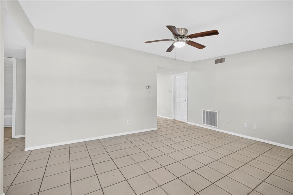 An empty room with light-colored walls, a ceiling fan, and beige tiled flooring — 11015 MARTHA AVENUE, PORT RICHEY, FL