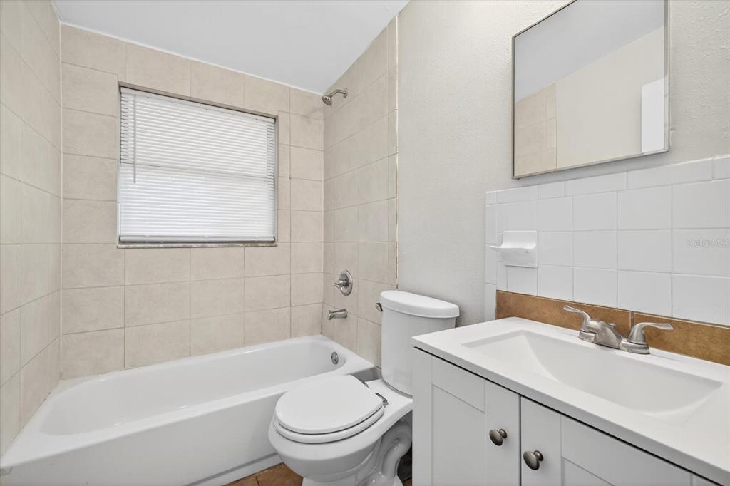 A bathroom featuring a white vanity, a toilet, and a tiled bathtub shower combination — 11015 MARTHA AVENUE, PORT RICHEY, FL