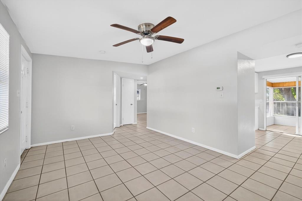 A bright, empty room features light gray walls, beige tile flooring, and a ceiling fan — 11015 MARTHA AVENUE, PORT RICHEY, FL