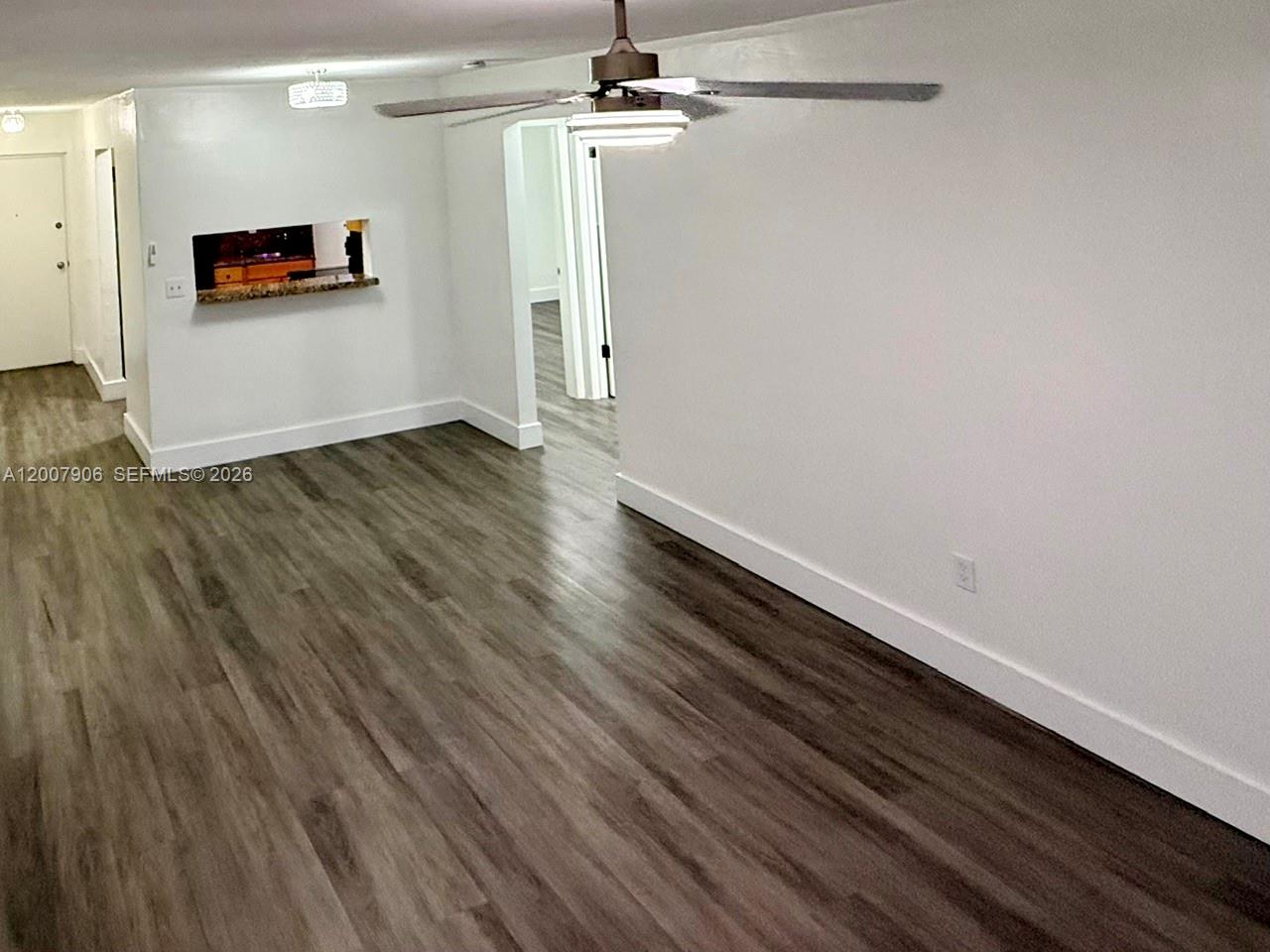 An interior view shows a living area with wood-look flooring, white walls, and a ceiling fan — 1945 NW 29th St # A8, Miami FL 33142, MIAMI, FL