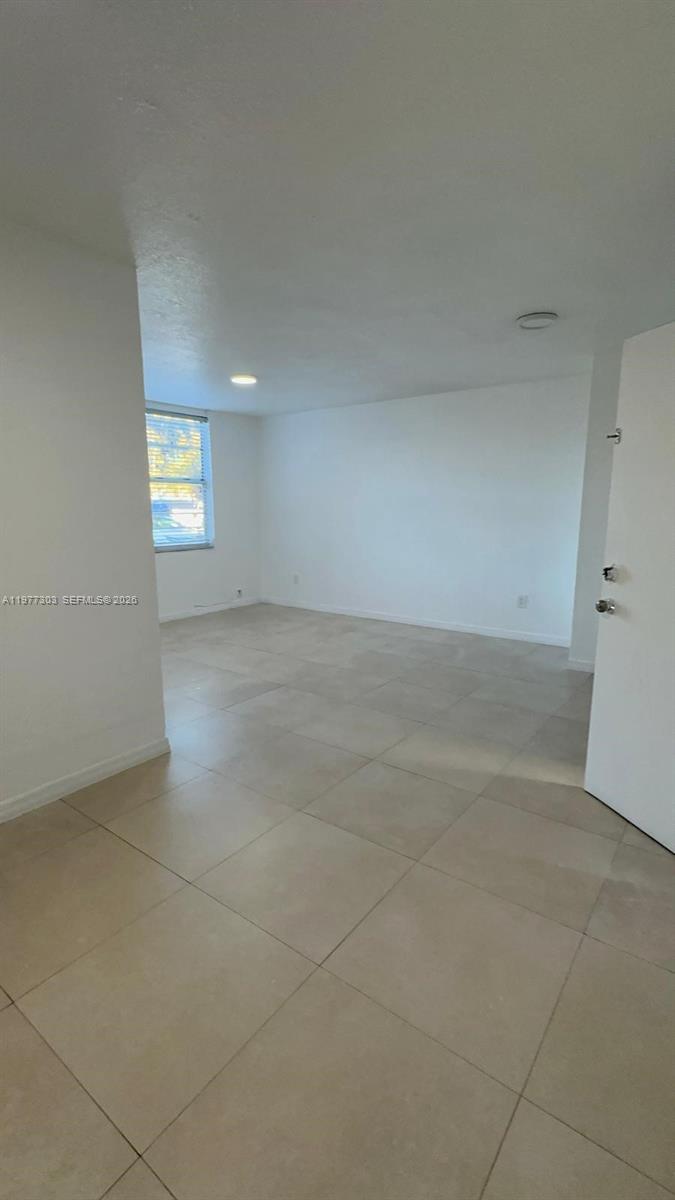 An empty room features white walls, a single window, and light-colored tile flooring — 1885 W 56th St # 112, Hialeah FL 33012, HIALEAH, FL
