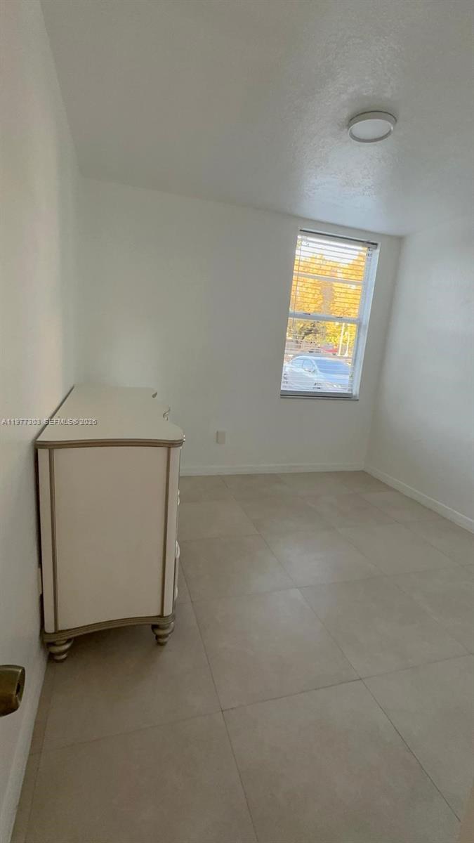 A bedroom features white walls, light-colored tile flooring, and a single window with blinds — 1885 W 56th St # 112, Hialeah FL 33012, HIALEAH, FL