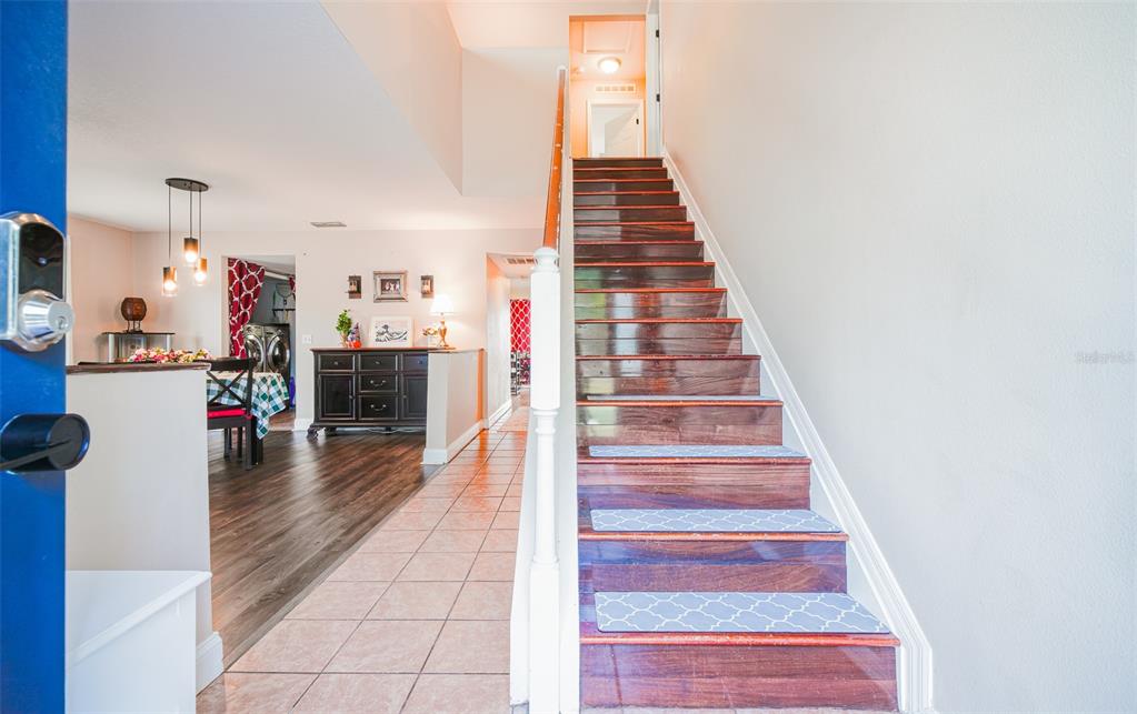 An entryway features a staircase with wood treads and patterned runners beside a tiled floor — 613 LOBELIA DRIVE, DAVENPORT, FL