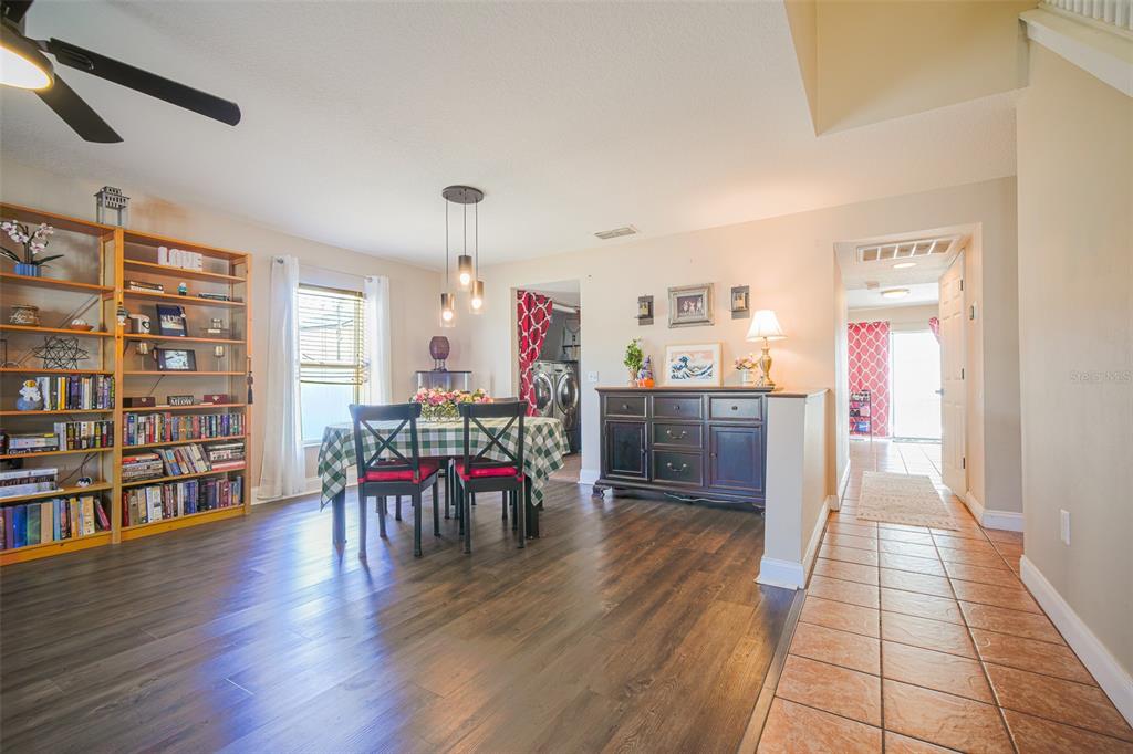 A dining area with wood flooring, a bookshelf, and a dark wood buffet cabinet — 613 LOBELIA DRIVE, DAVENPORT, FL
