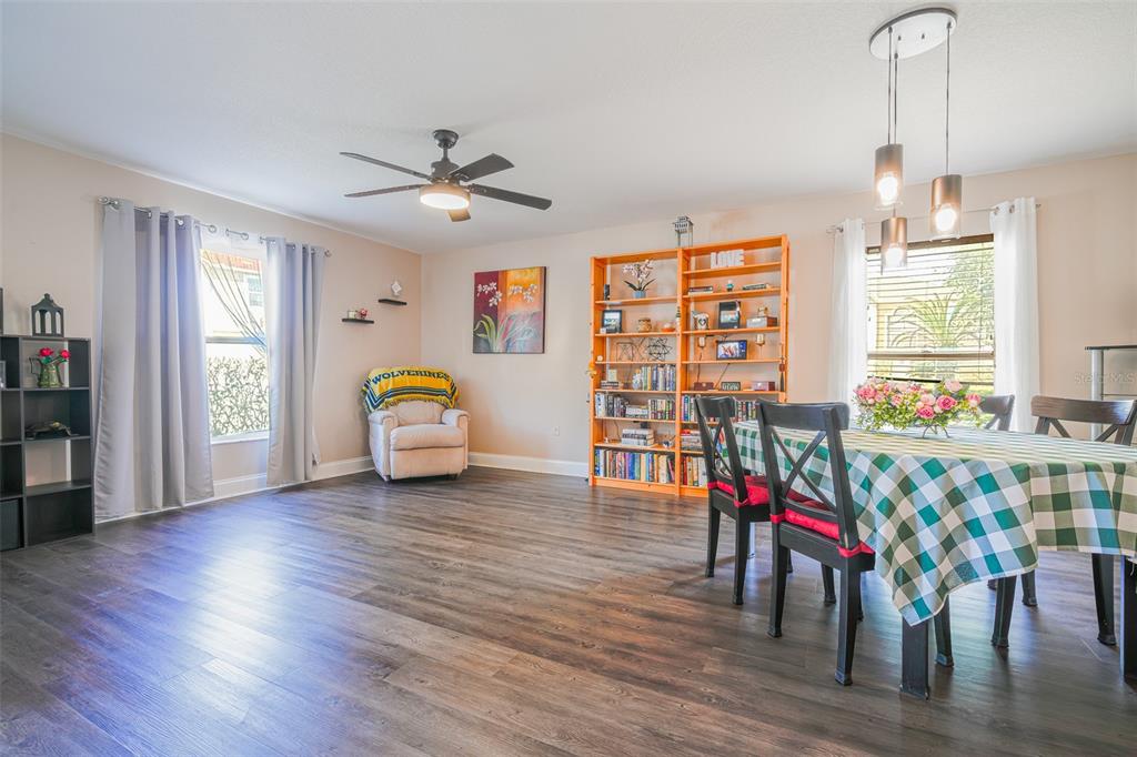 A dining room with wood-look flooring, a checkered tablecloth, and an orange bookshelf — 613 LOBELIA DRIVE, DAVENPORT, FL