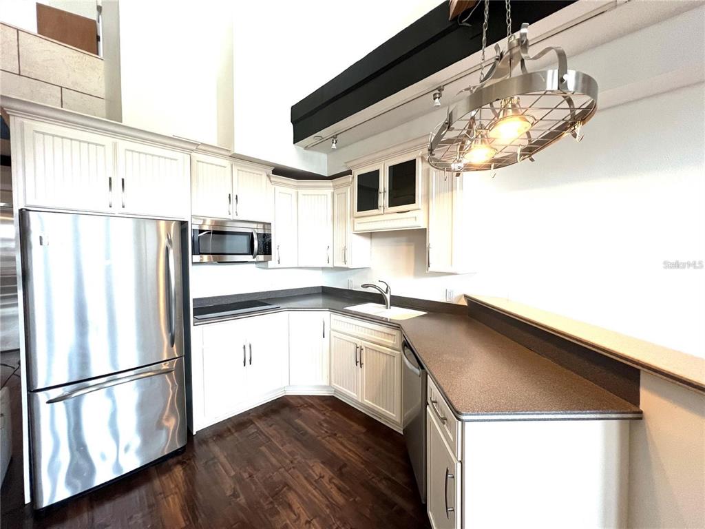A kitchen features white cabinetry, stainless steel appliances, dark countertops, and a hanging light fixture — 101 PALM HARBOR PARKWAY UNIT A404, PALM COAST, FL