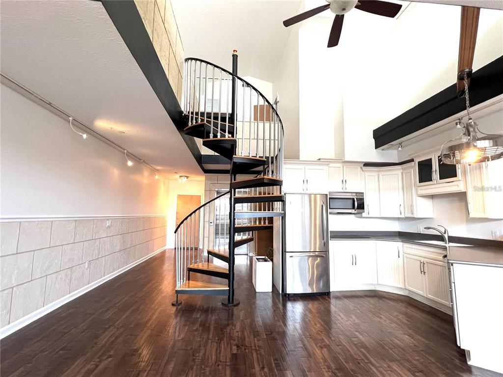 A spiral staircase stands in a kitchen and living area with dark wood flooring — 101 PALM HARBOR PARKWAY UNIT A404, PALM COAST, FL