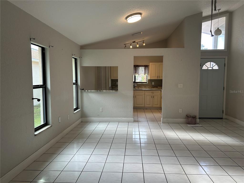 A tiled living area features a pass-through window to the kitchen and a front door — 9814 PINEY POINT CIRCLE, ORLANDO, FL