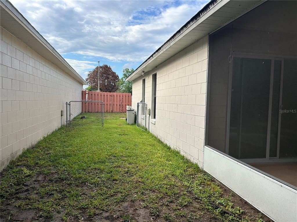A narrow grassy side yard sits between two concrete block houses with a fence — 9814 PINEY POINT CIRCLE, ORLANDO, FL