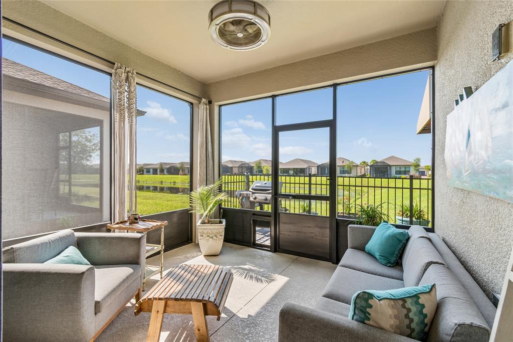 A screened-in patio features gray furniture, a wooden coffee table, and views of a pond — 779 VIA COMO ST, POINCIANA, FL