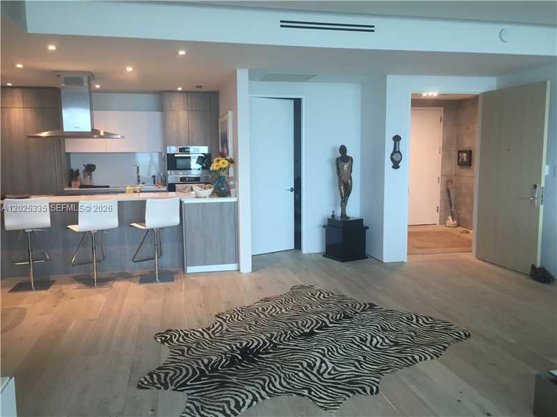 A modern kitchen with a breakfast bar, light wood floors, and a zebra-print rug — 350 OCEAN DR # 304N, Key Biscayne FL 33149, KEY BISCAYNE, FL