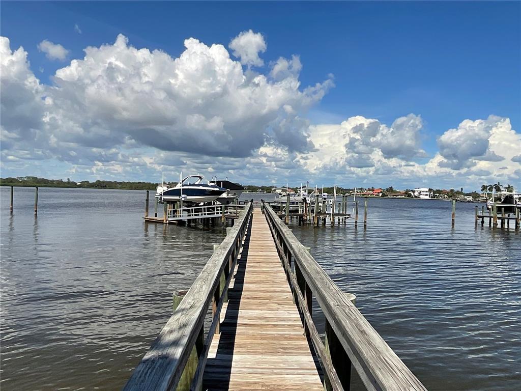 A wooden pier extends into a body of water with docked boats under a cloudy sky — 0 SHARSWOOD LANE, SARASOTA, FL