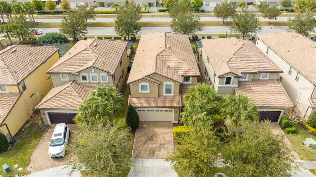 An aerial view of three suburban houses with tiled roofs and paved driveways — 9013 RHODES STREET, KISSIMMEE, FL