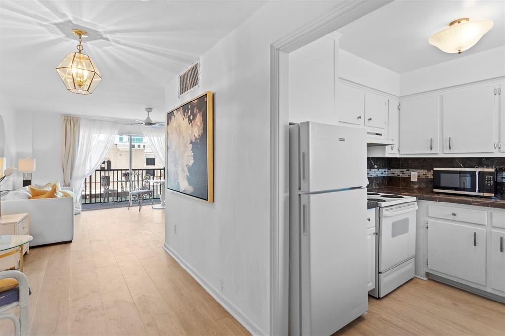 A view from a kitchen looking into a living area with a balcony beyond — 750 BURLINGTON AVENUE N UNIT 3C, ST PETERSBURG, FL