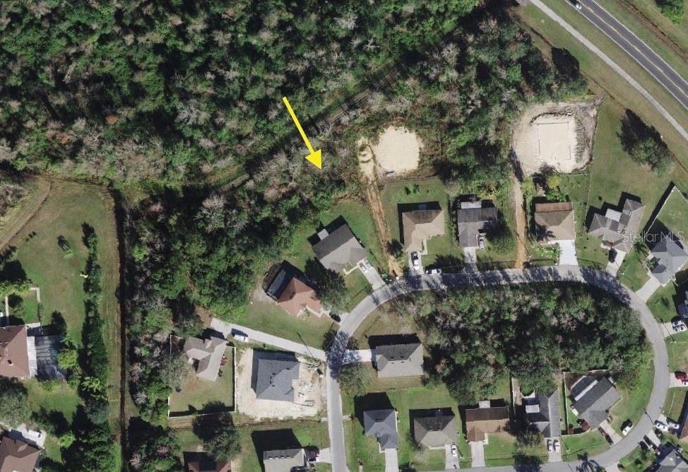 This aerial view shows a residential neighborhood with several houses and a wooded lot — 0 MILAN DRIVE, KISSIMMEE, FL