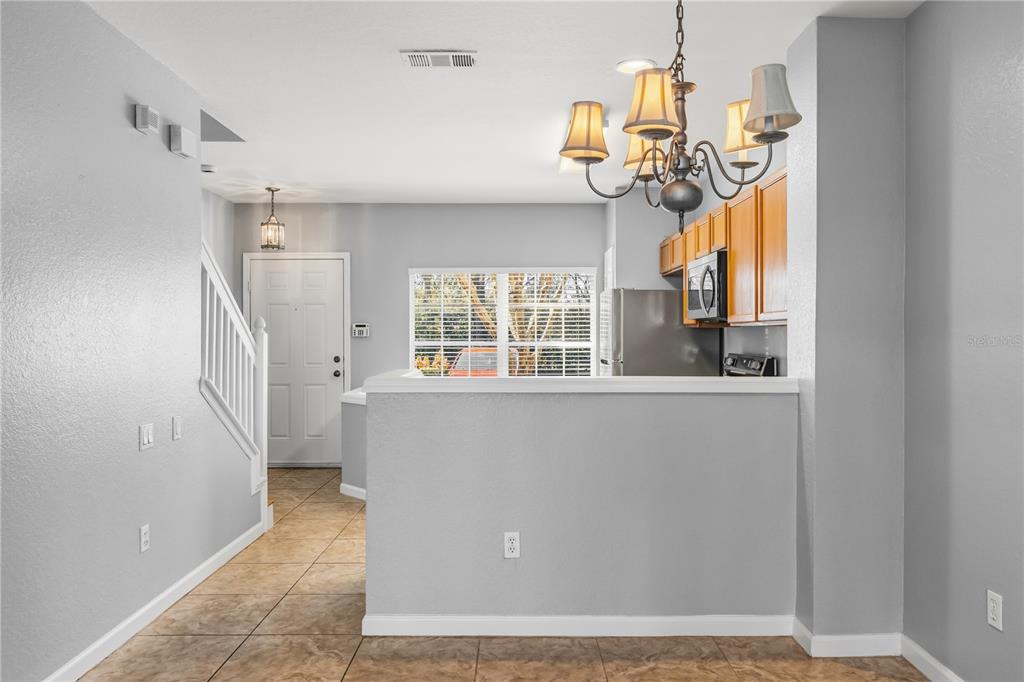 A view of a kitchen with wooden cabinets, a chandelier, and a tiled entryway — 1450 STOCKTON DRIVE, SANFORD, FL