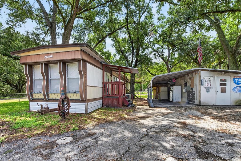 A mobile home with a front porch sits next to a detached carport and shed — 10227 OAK AVENUE, TAMPA, FL