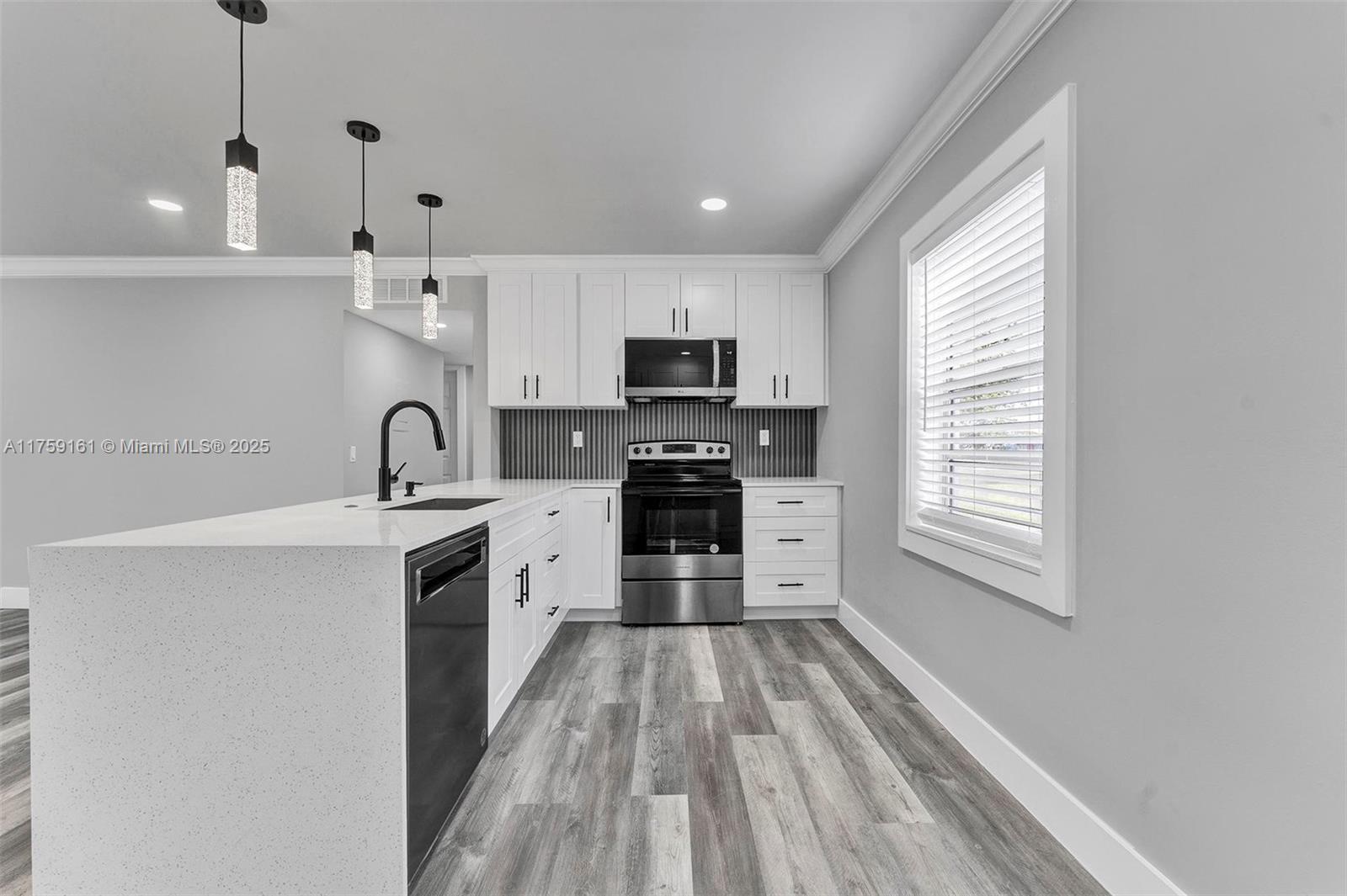 A modern kitchen features white cabinets, stainless steel appliances, a quartz island, and wood-look flooring — 38 Flanders A # 38, Delray Beach FL 33484, DELRAY BEACH, FL