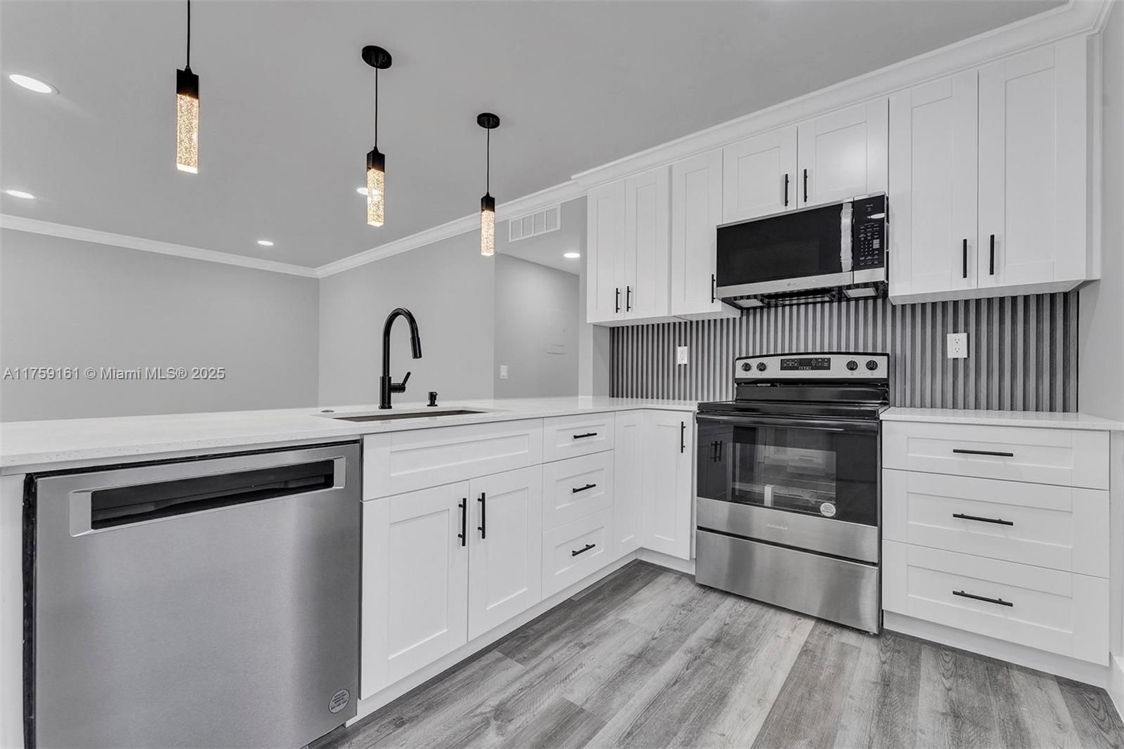 A modern kitchen features white cabinets, stainless steel appliances, and a gray-striped backsplash — 38 Flanders A # 38, Delray Beach FL 33484, DELRAY BEACH, FL