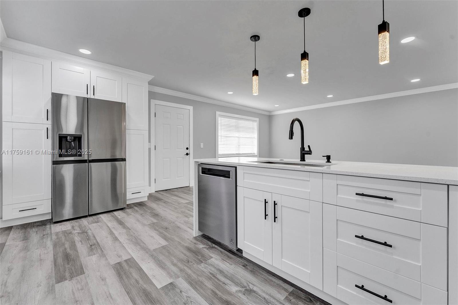 A modern kitchen features white cabinetry, stainless steel appliances, and a central island with seating — 38 Flanders A # 38, Delray Beach FL 33484, DELRAY BEACH, FL