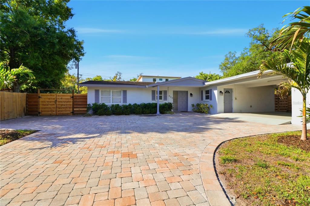 A single-story house features a paved driveway, a covered carport, and a wooden fence — 630 CORWOOD DRIVE, SARASOTA, FL